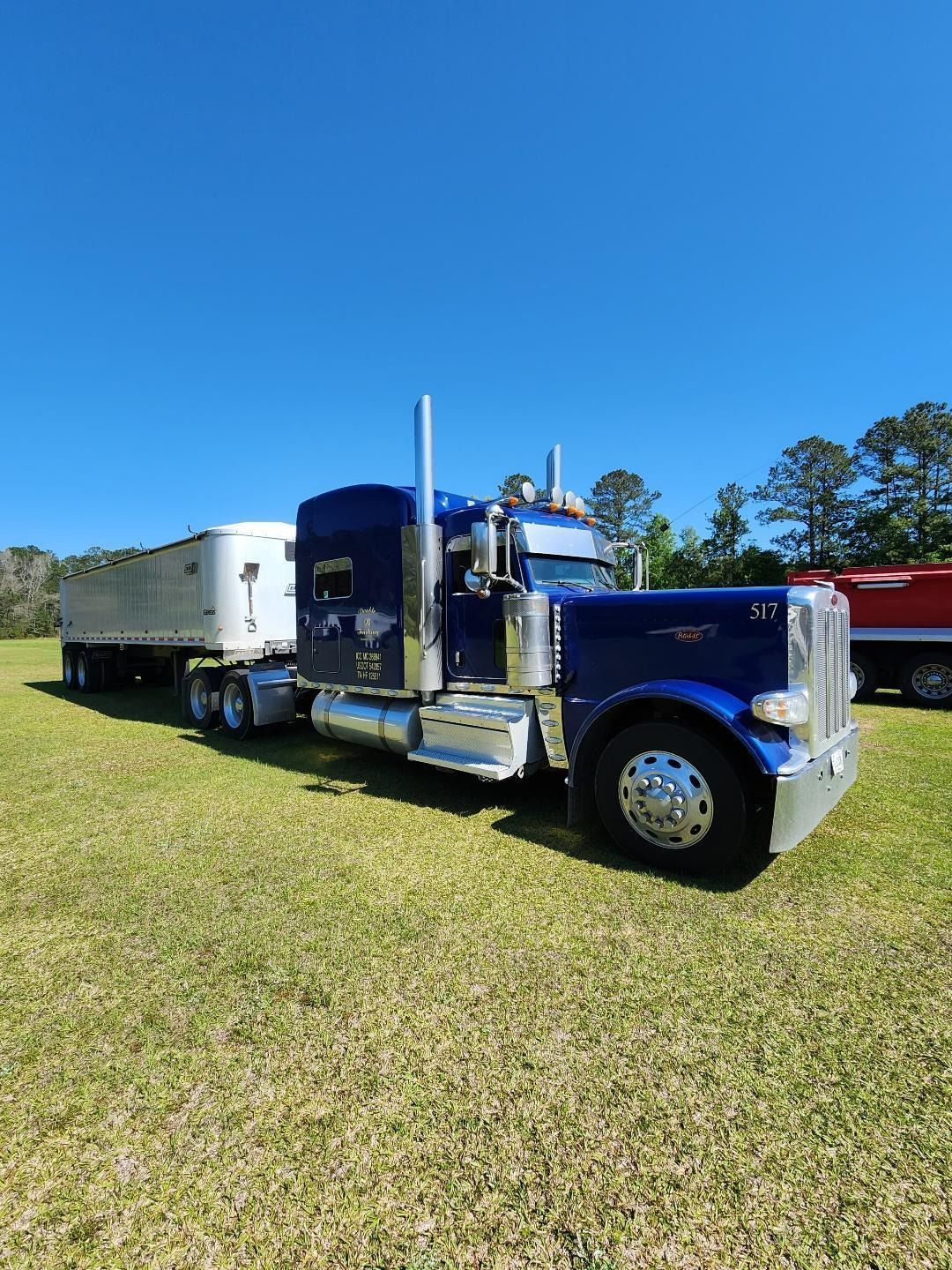 A Shiny Blue Semi-truck With a White Trailer Parked on a Grassy Field — Valentine Detailing LLC in Walterboro, SC