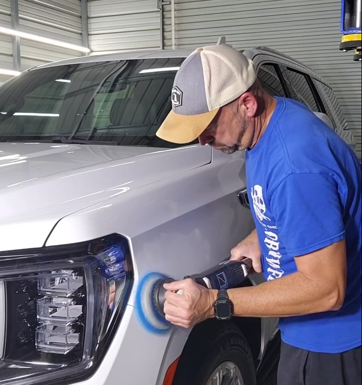 A Person Uses an Electric Buffer to Polish the Front Fender of a White SUV — Valentine Detailing LLC in Walterboro, SC