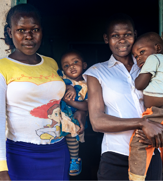Two moms holding their children outside Kenya school.