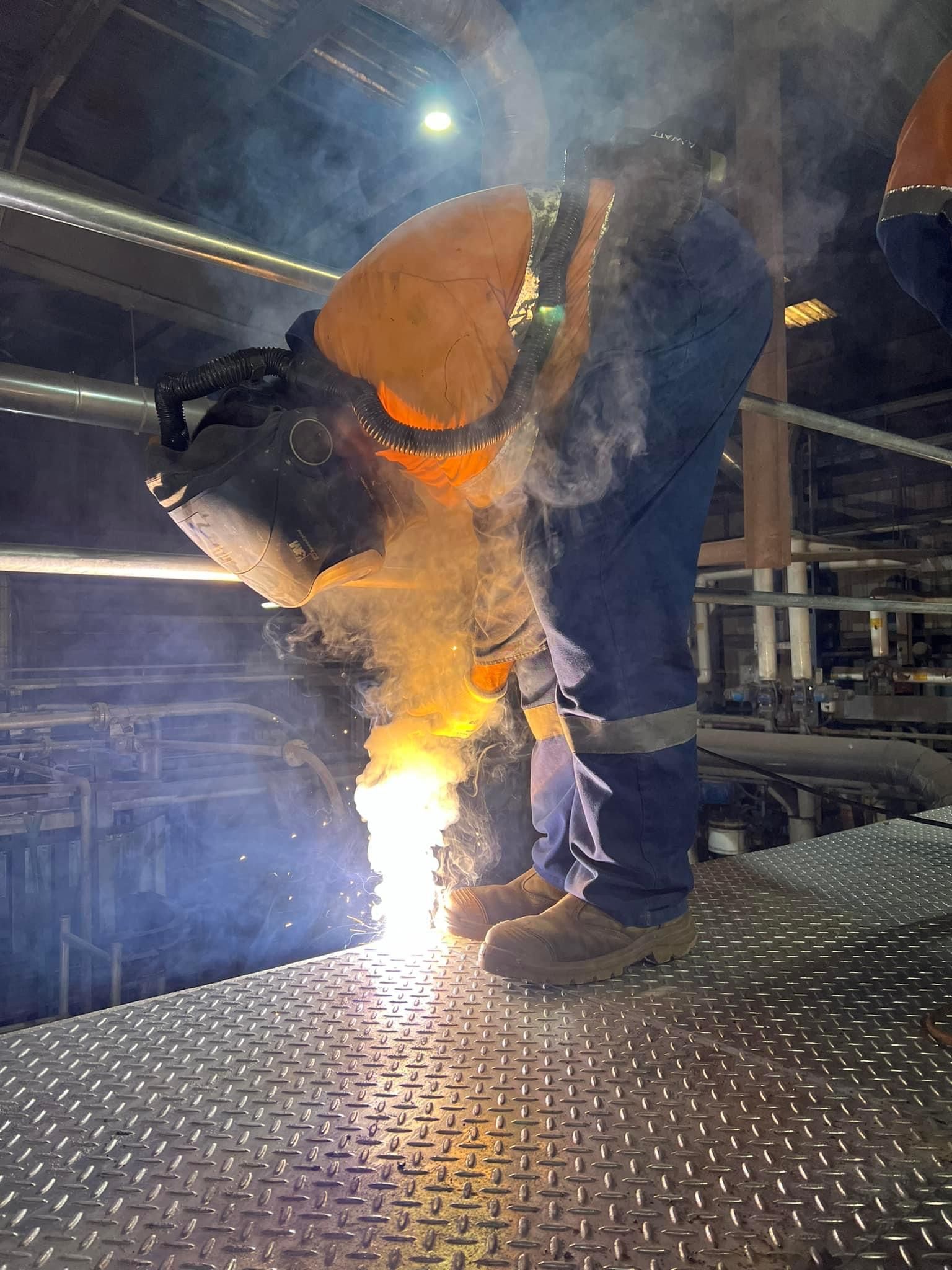 A Man Wearing A Welding Mask Is Welding A Metal Platform — Absolute Steel Fabrication & Welding In East Wagga Wagga, NSW