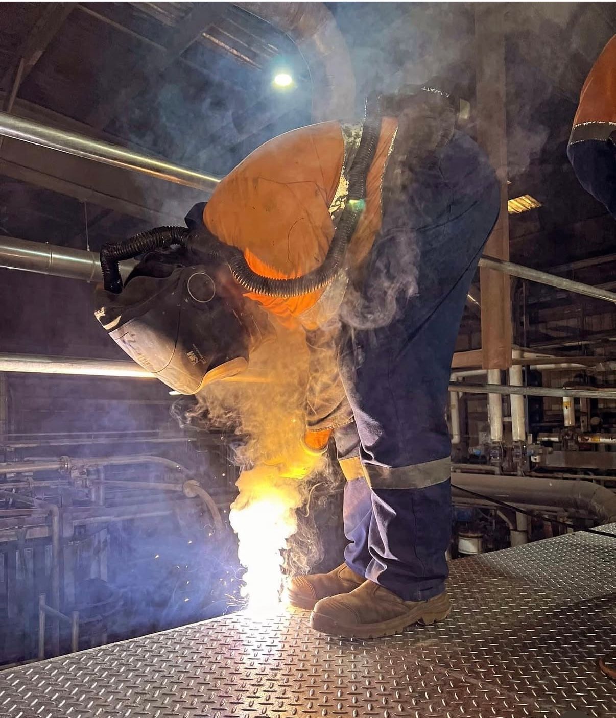 A Man Is Welding A Piece Of Metal In A Factory — Absolute Steel Fabrication & Welding In East Wagga Wagga, NSW