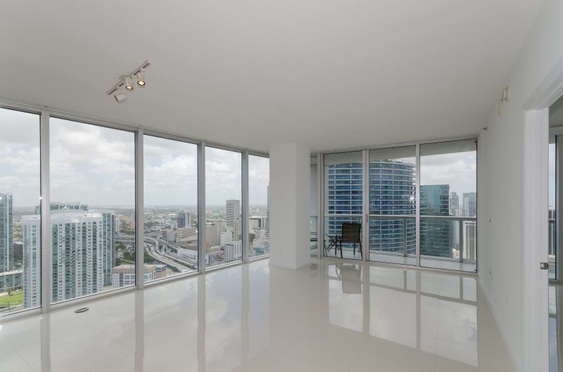 An empty apartment with a lot of windows and a view of the city.