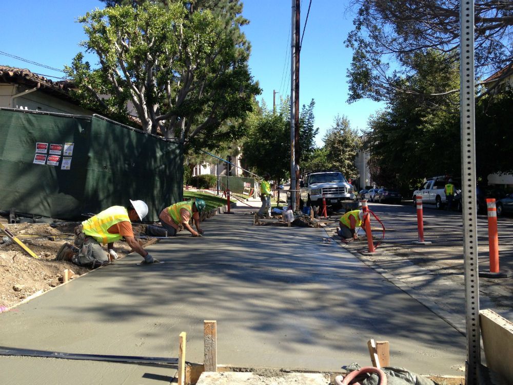 A group of construction workers are working on a sidewalk