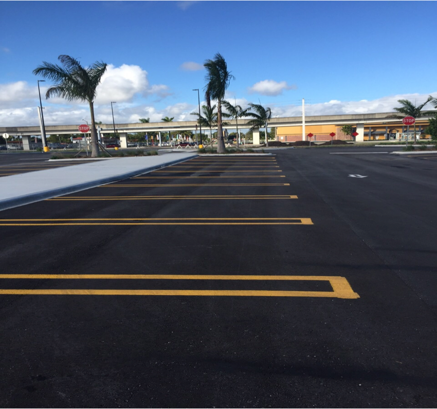 A parking lot with yellow lines and palm trees in the background