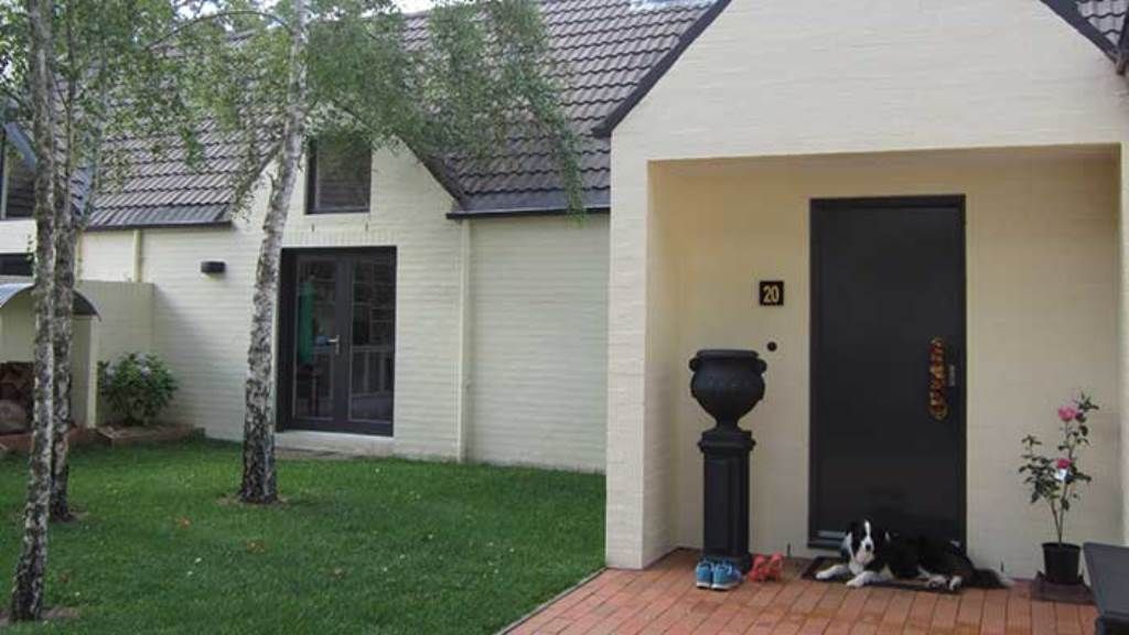 A white house with a black door and a dog on the porch — GMT Builders Pty Ltd in Milton Park, NSW