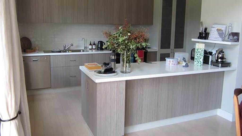 A kitchen with a large island and a vase of flowers on the counter — GMT Builders Pty Ltd in Bowral, NSW