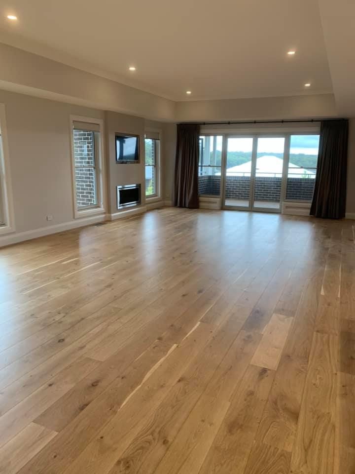 An Empty Living Room with Hardwood Floors and Sliding Glass Doors — GMT Builders Pty Ltd in Bowral, NSW