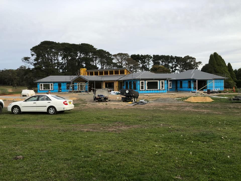 A White Car Is Parked in Front of A Large House Under Construction — GMT Builders Pty Ltd in Kangaloon, NSW