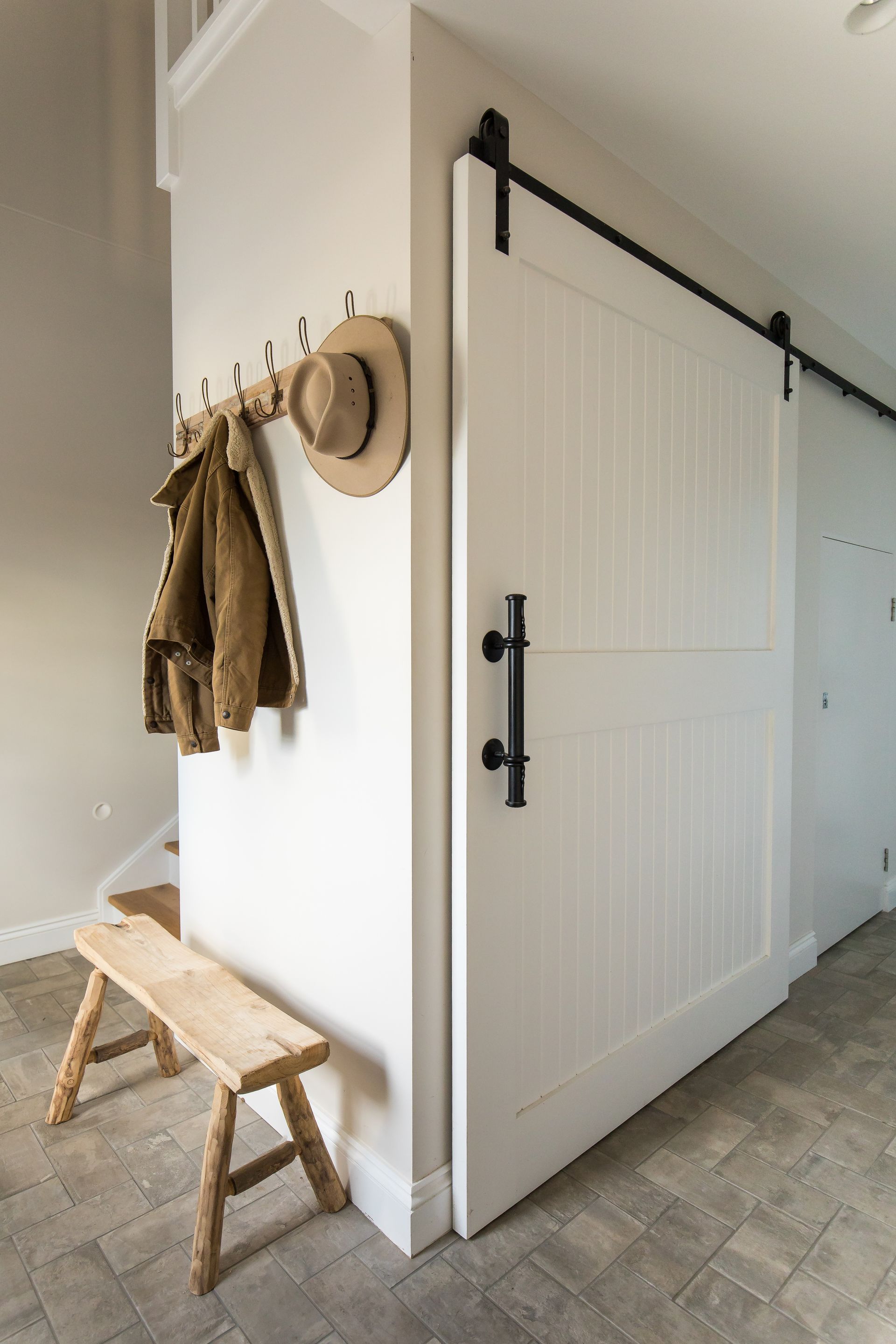 A Hat And Jacket On Hooks Above Timber Bench Seat Next To White Barn Door — GMT Builders Pty Ltd in Berrima, NSW