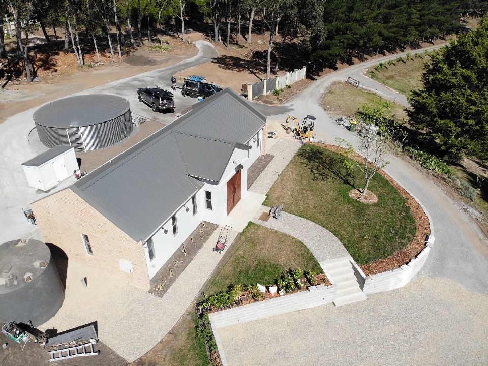 An aerial view of a house surrounded by trees and a road