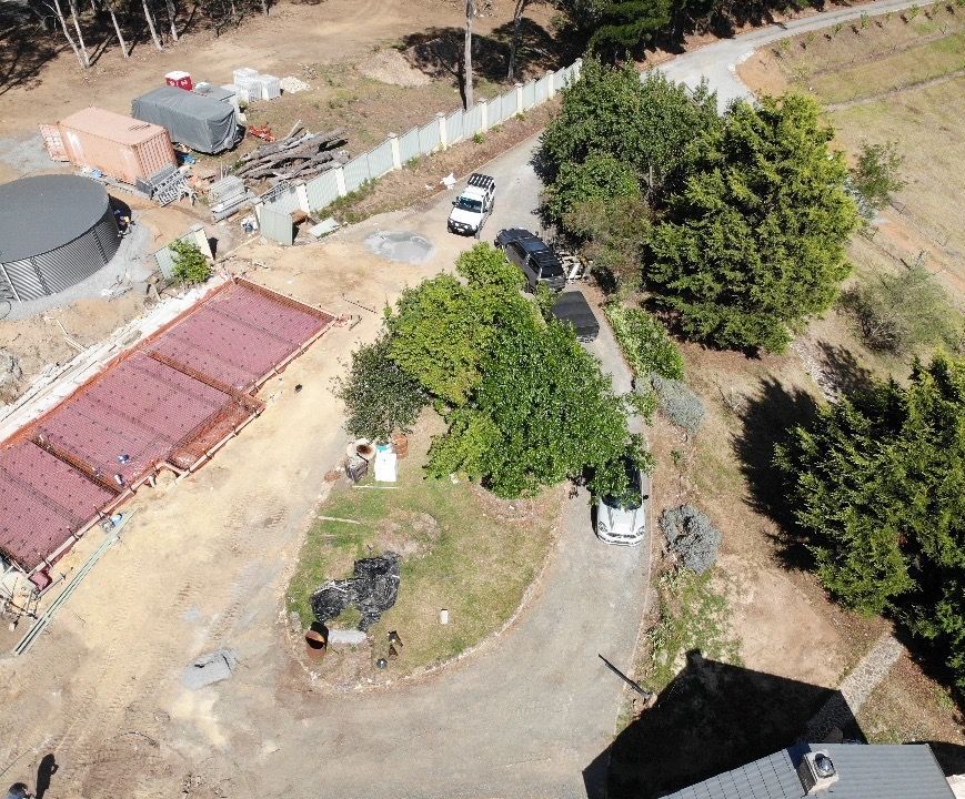 An aerial view of a house surrounded by trees and a road.