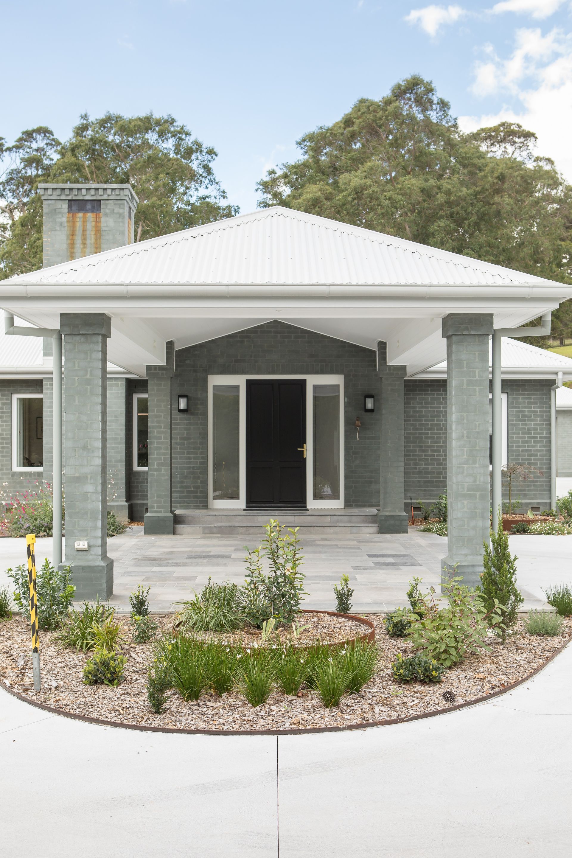 A Front View Of A Large Grey Brick House With A Black Door — GMT Builders Pty Ltd in Nowra, NSW