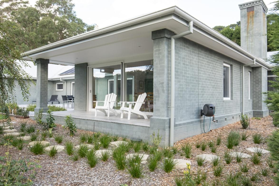 A Gray House with White Chairs on The Porch — GMT Builders Pty Ltd in Burradoo, NSW