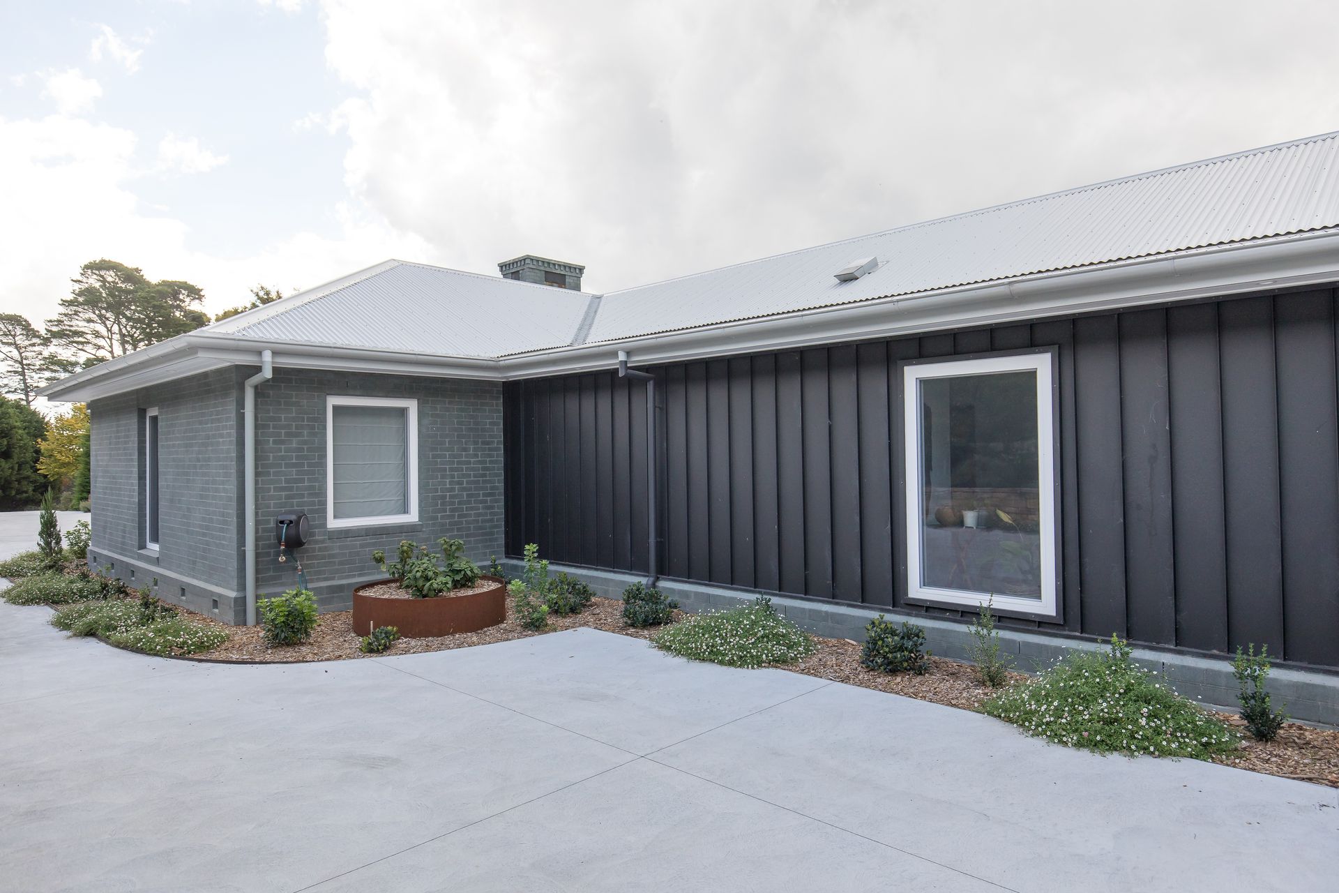 A large house with a black siding and a white roof — GMT Builders Pty Ltd in Nowra, NSW