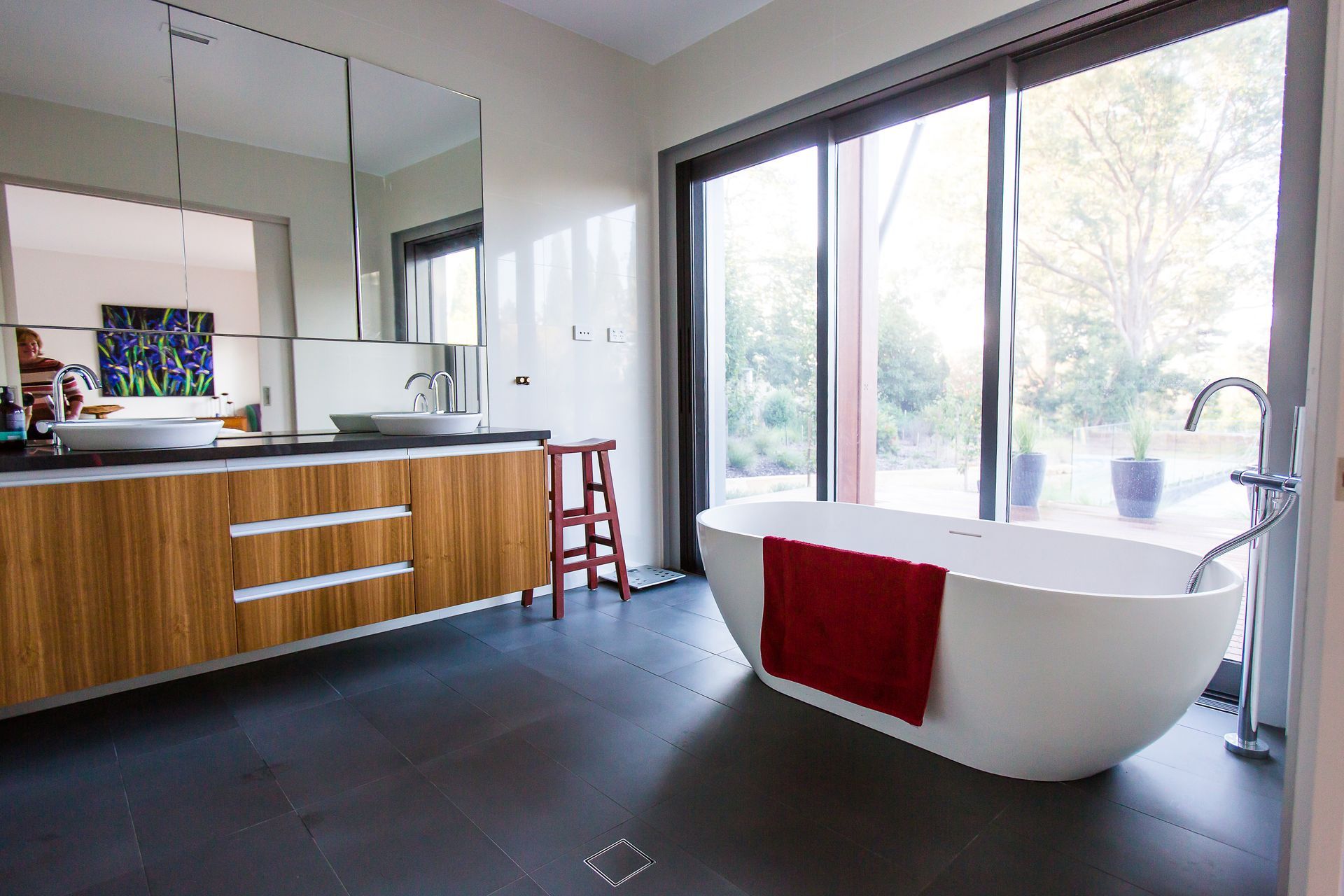 A bathroom with a bathtub, sink, mirror and sliding glass doors  — GMT Builders Pty Ltd in Sunninghill, NSW
