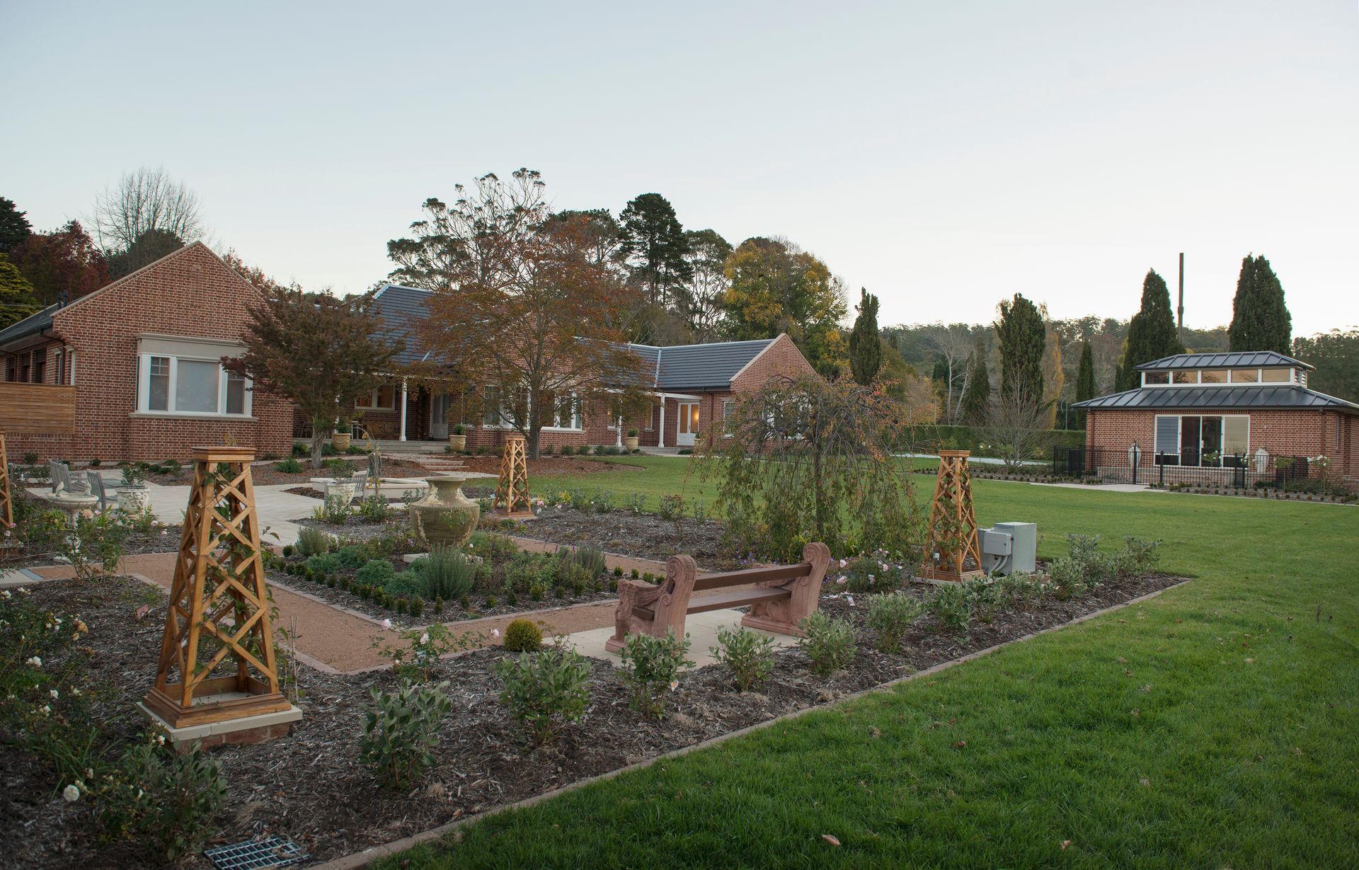 A garden with a brick building in the background — GMT Builders Pty Ltd in Bowral, NSW