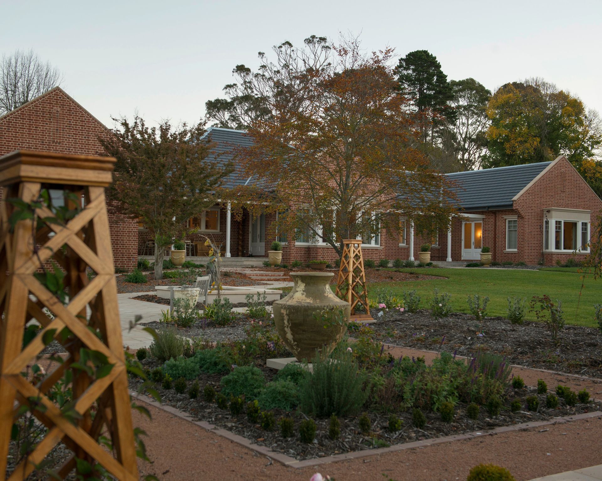 A large brick house with a garden in front of it — GMT Builders Pty Ltd in Bowral, NSW