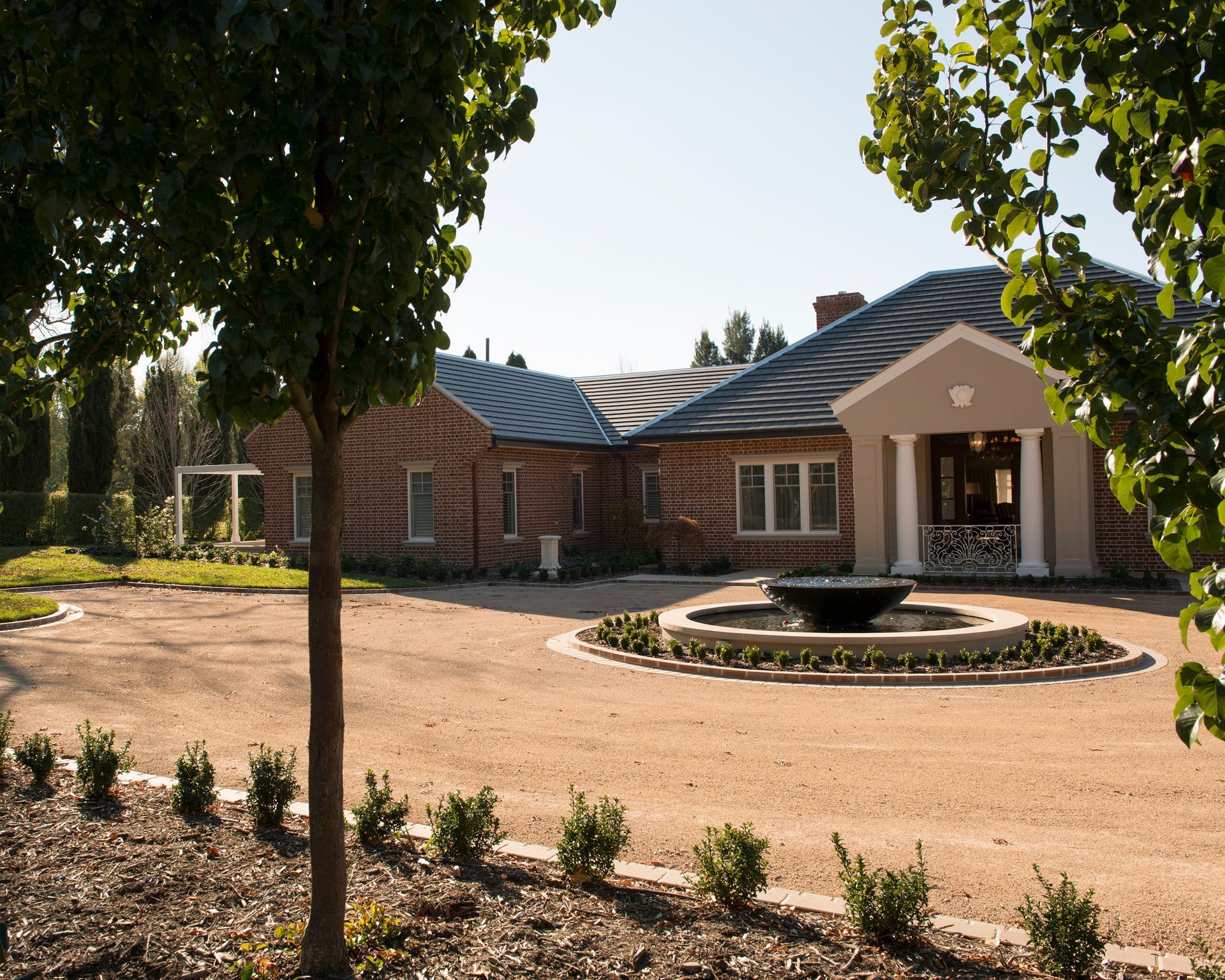 A large brick house with a fountain in front of it — GMT Builders Pty Ltd in Bowral, NSW
