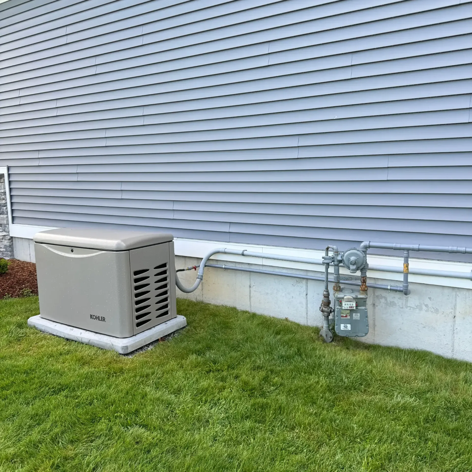 Pinette Plumbing - A generator is sitting in the grass next to a house.