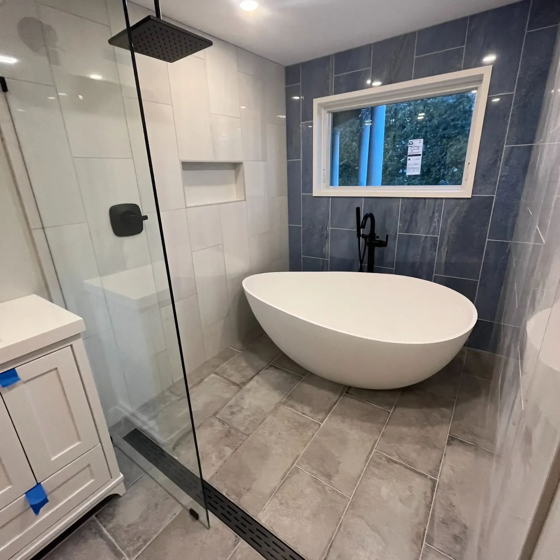 Pinette Plumbing - A bathroom with a tub and a shower with a window.