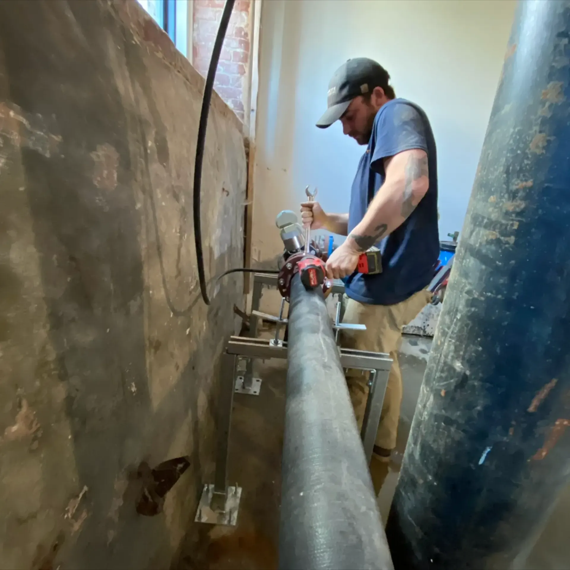 Pinette Plumbing - A man is working on a pipe with a drill.