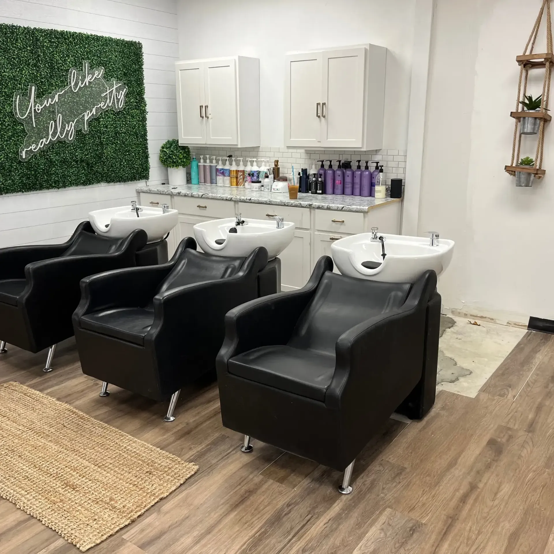 Pinette Plumbing - A row of black chairs and sinks in a salon.