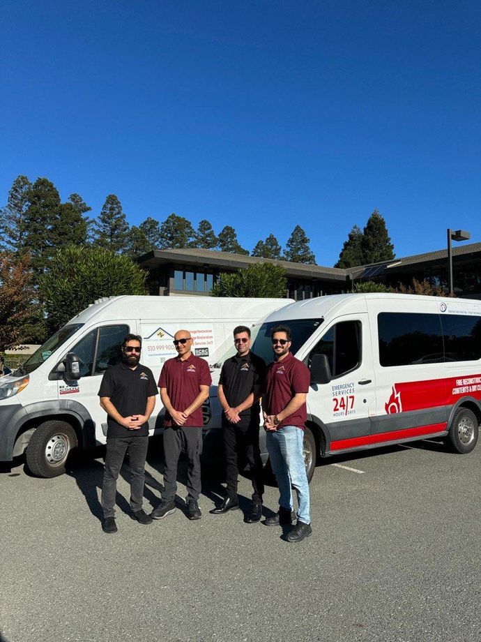 A group of men are standing in front of three vans.