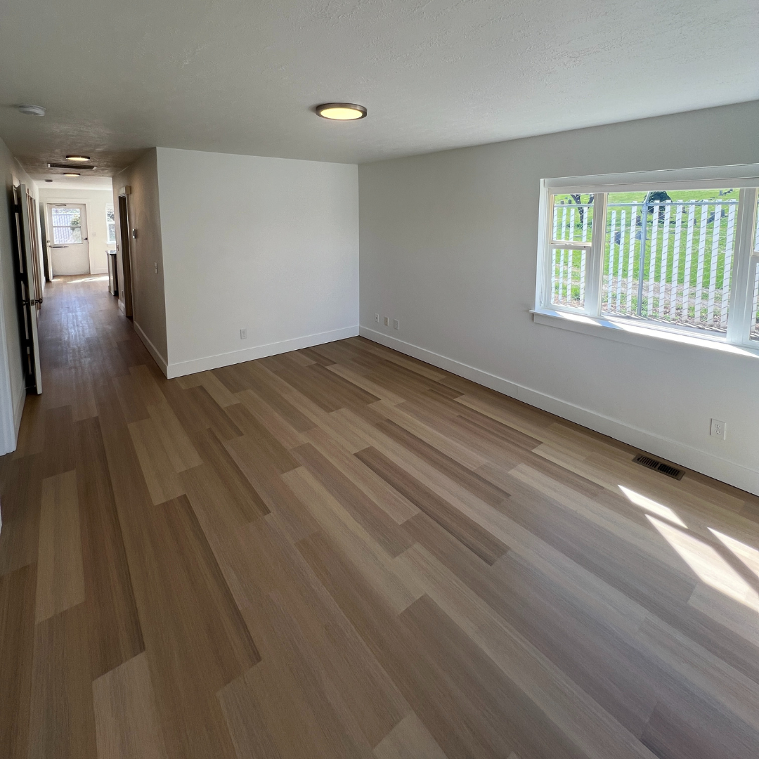 An empty living room with hardwood floors and white walls.