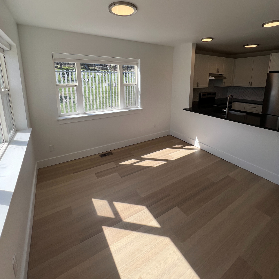 An empty room with hardwood floors and a large window
