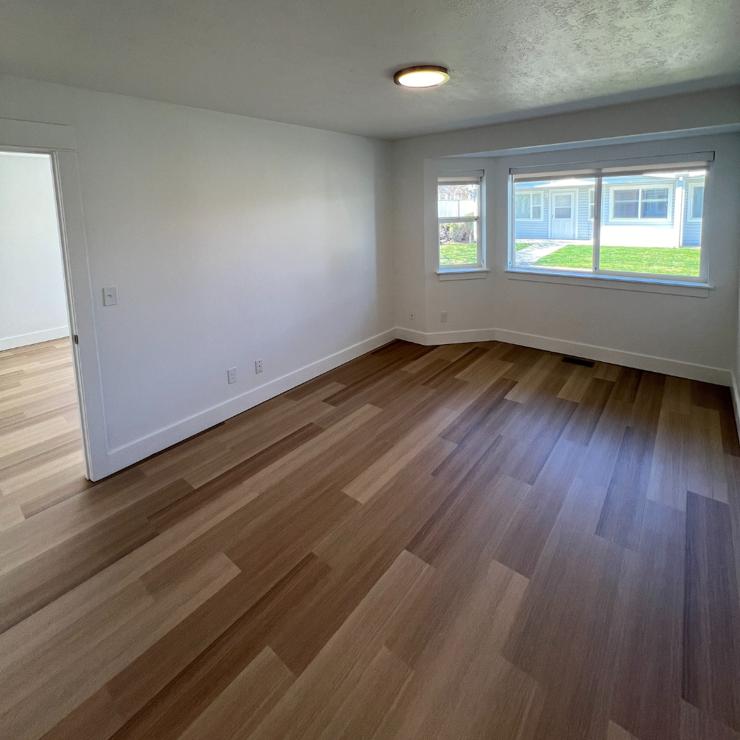 An empty room with hardwood floors and white walls.