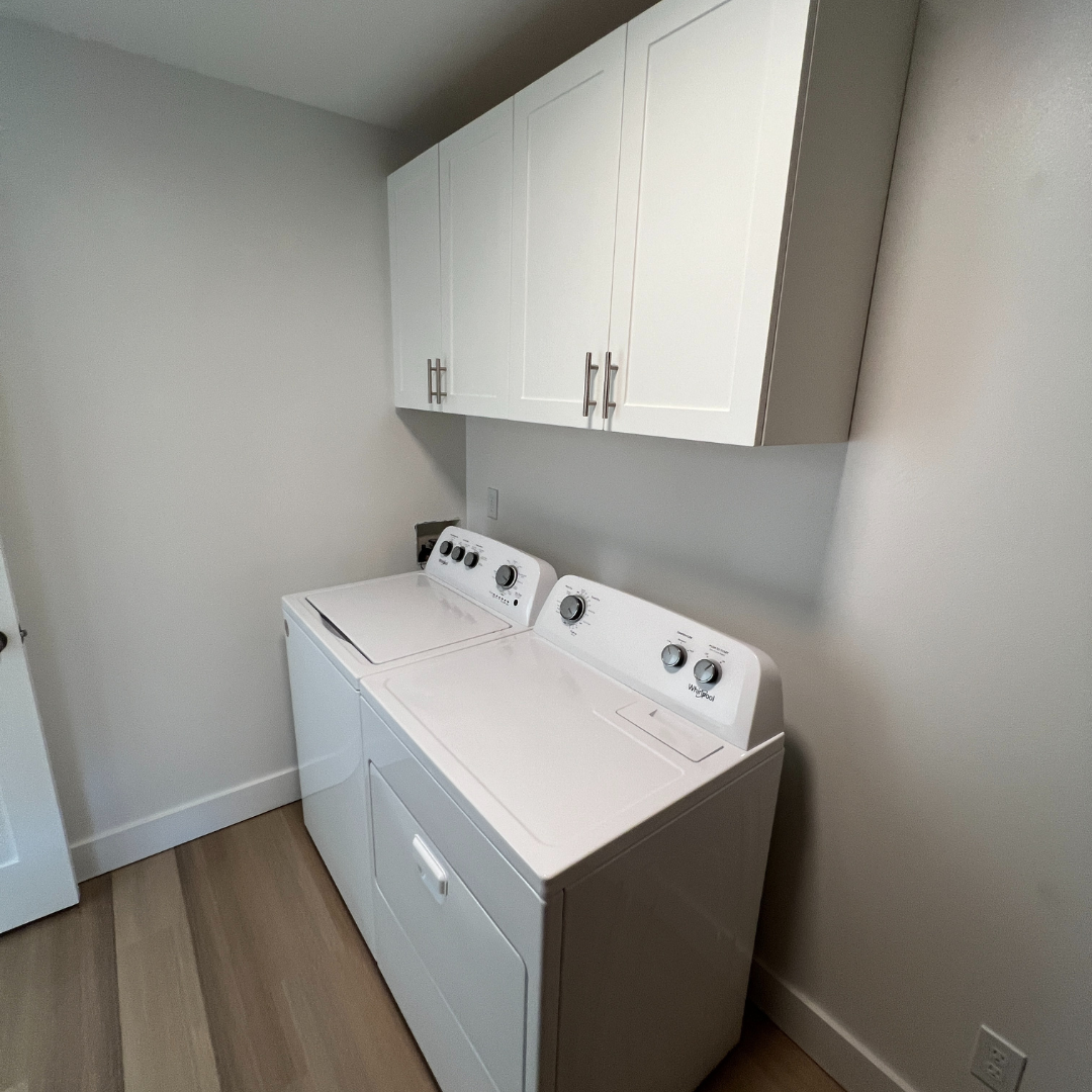 A laundry room with a washer and dryer and white cabinets