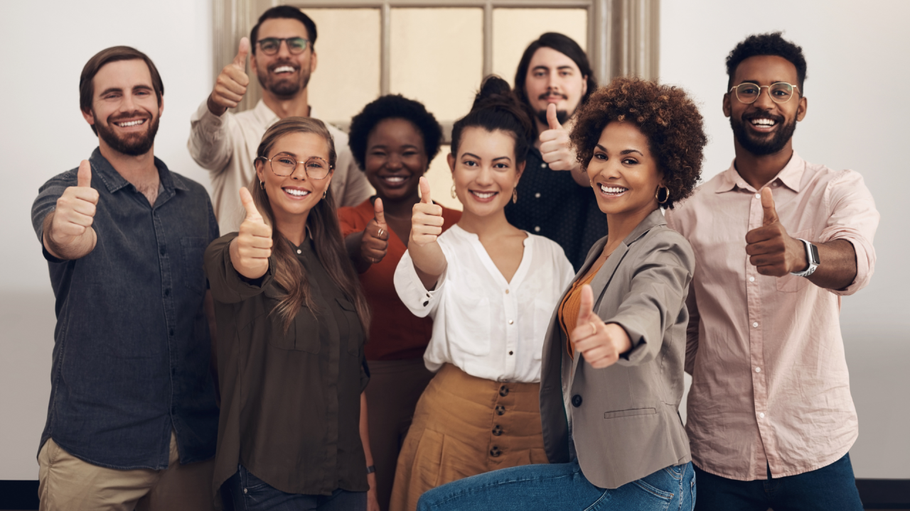 A group of people are standing next to each other and giving a thumbs up.