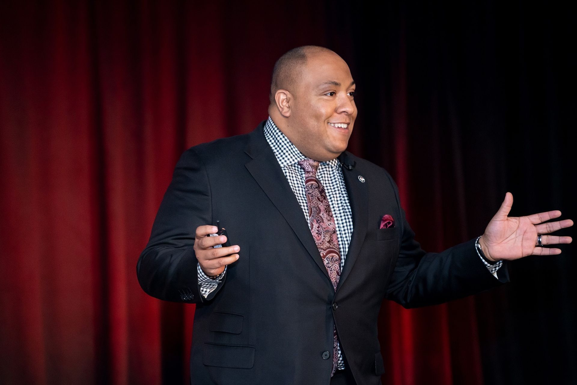 A man in a suit and tie is standing on a stage giving a speech.