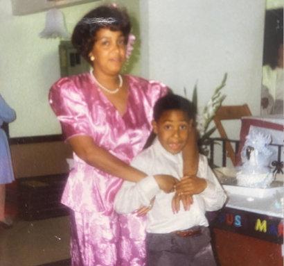 A woman in a pink dress holds a young boy in her arms