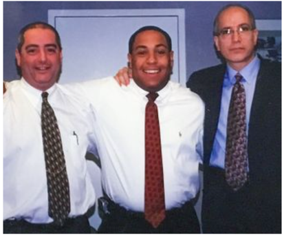 Three men in suits and ties pose for a picture