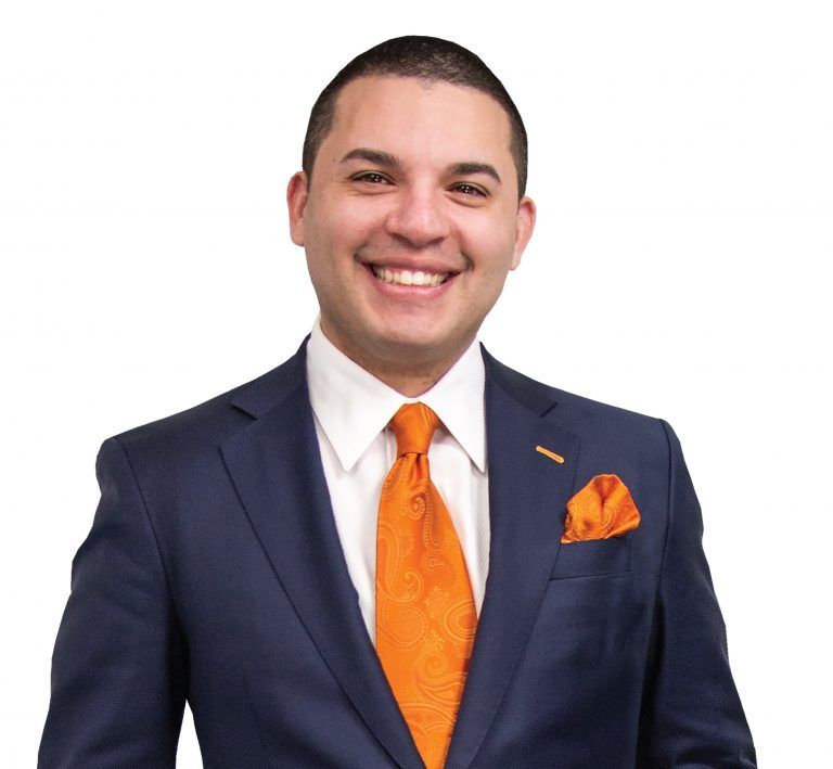 A man in a blue shirt and tie is smiling for the camera.