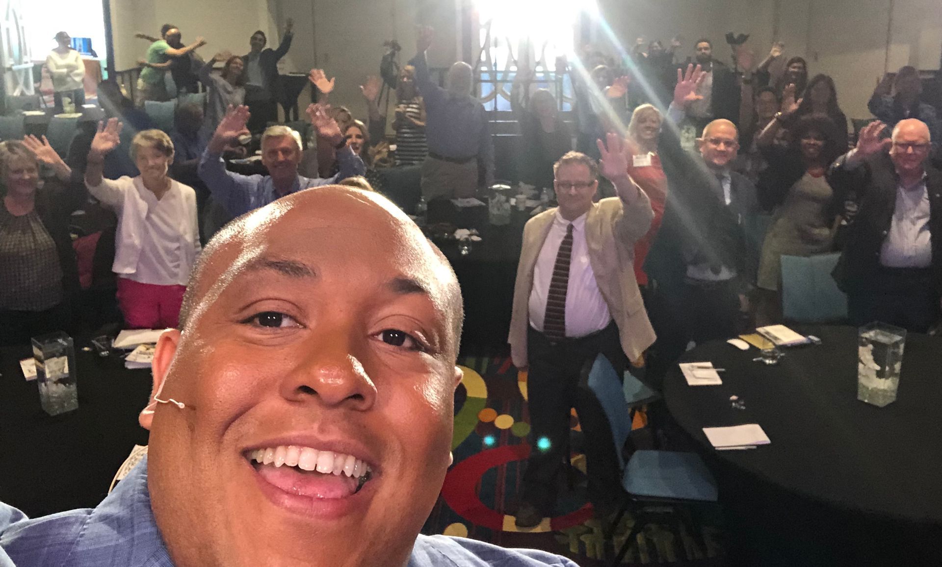A man is taking a selfie in front of a crowd of people.