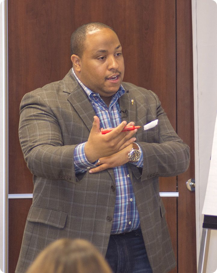 A man in a suit is giving a presentation to a group of people.