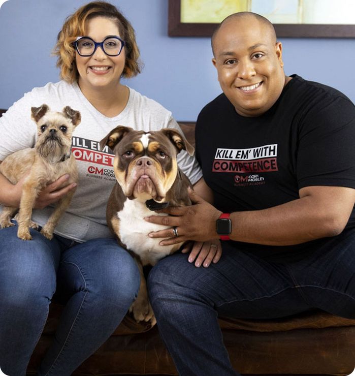 A man and a woman are sitting on a couch with two dogs.