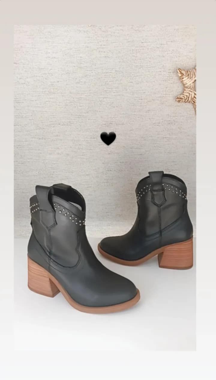 Un par de botas de vaquero negras sobre una superficie blanca.