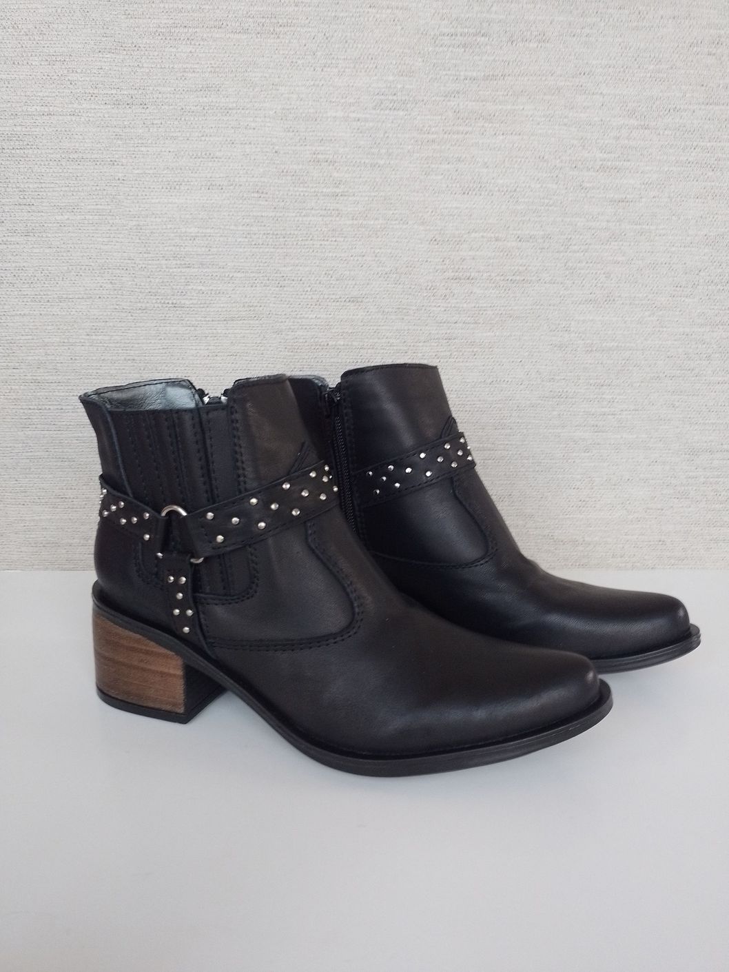 Un par de botas de vaquero negras sobre una superficie blanca.