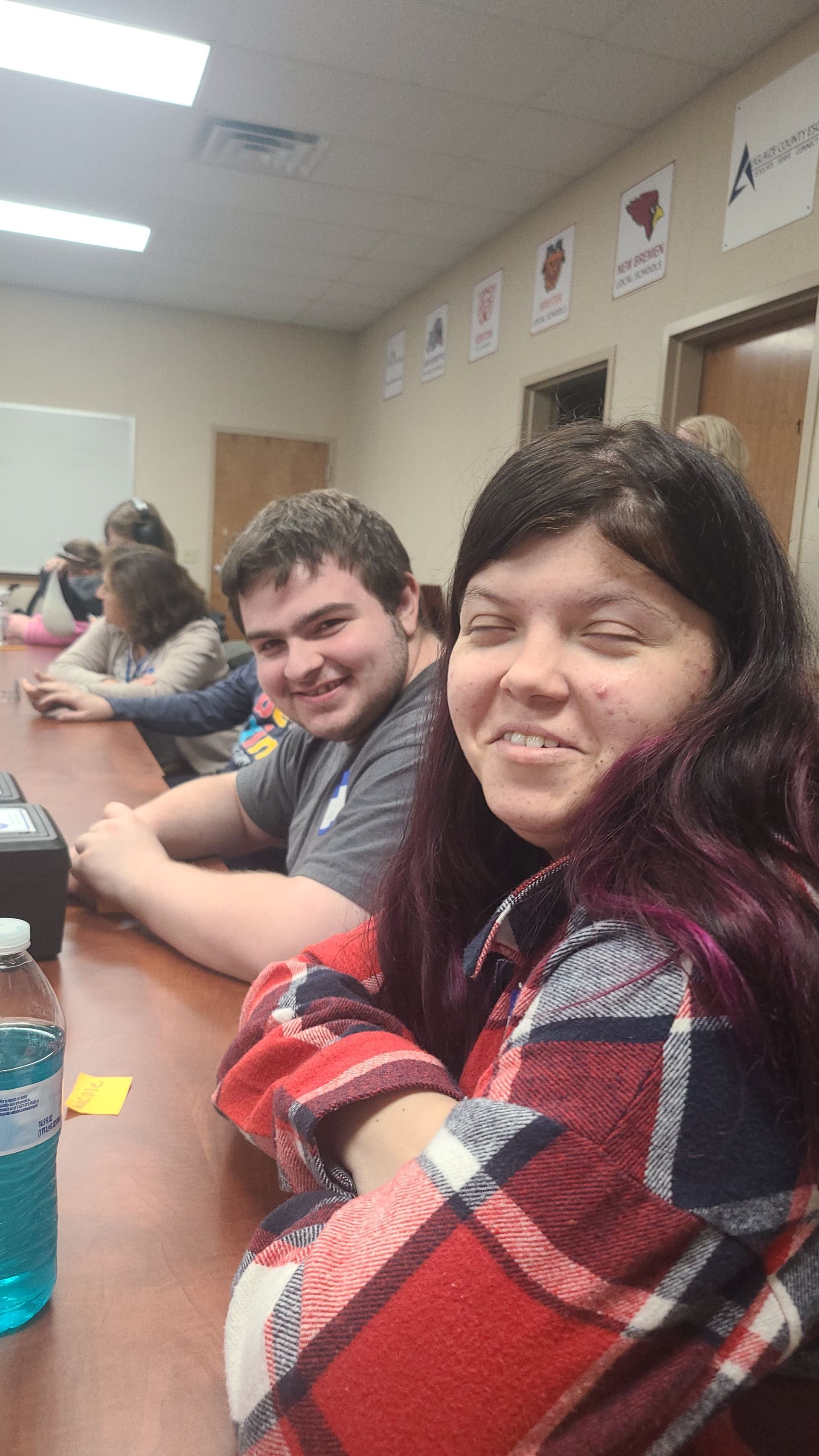 Two men are working on a table with papers and a stapler.