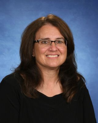 A group of women are posing for a picture in front of a brick wall.