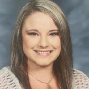 A woman is smiling for a picture and wearing a necklace. This is Alysha Caudill.