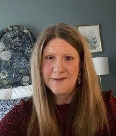 A woman is taking a selfie in front of a bed in a bedroom.