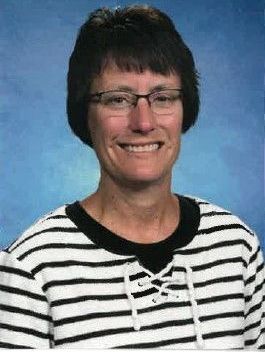 A woman wearing glasses and a striped shirt is smiling for a picture.
