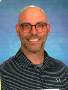 A woman in a red floral shirt is smiling for the camera.