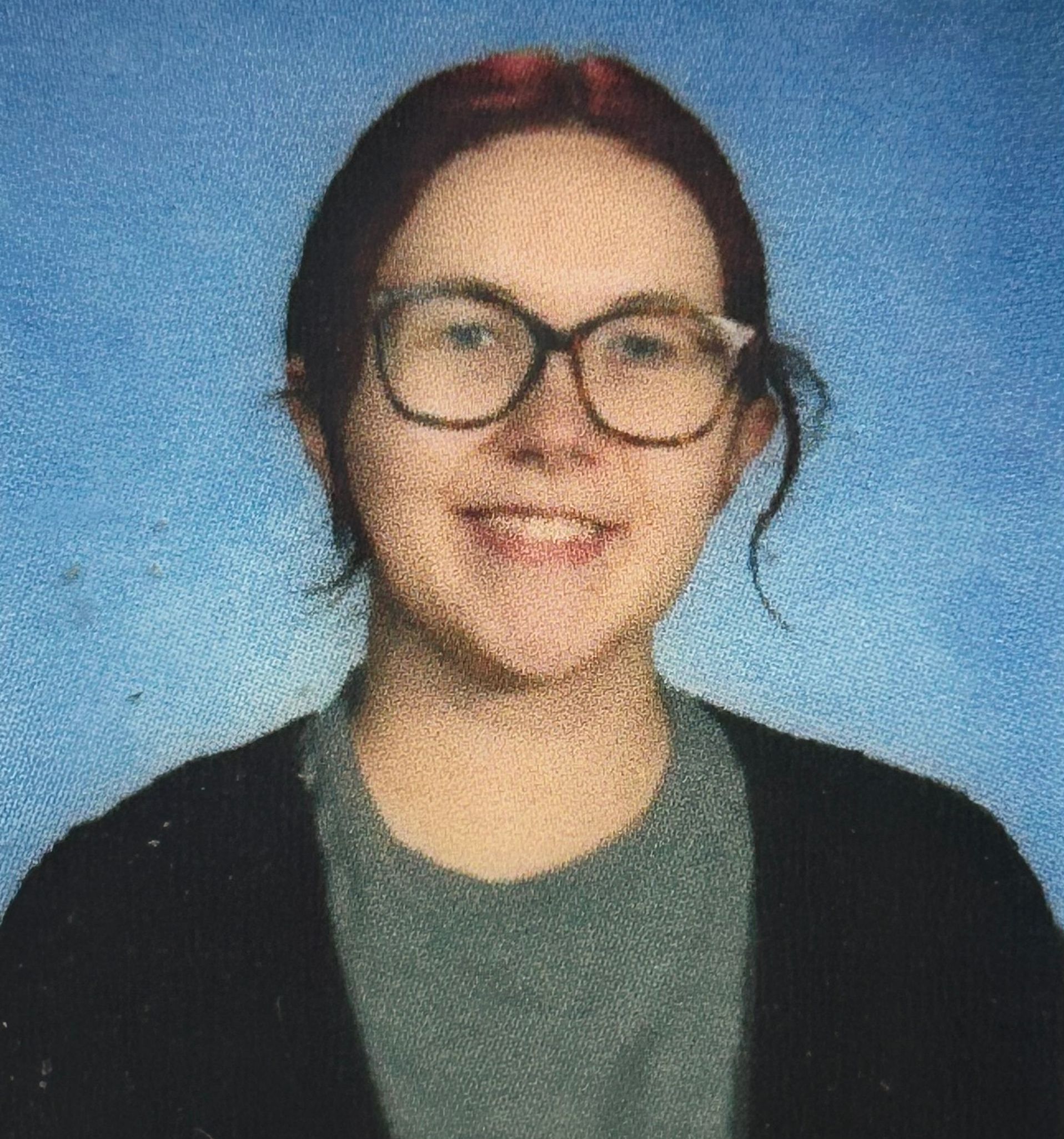 A woman wearing glasses and a black jacket is smiling for the camera.