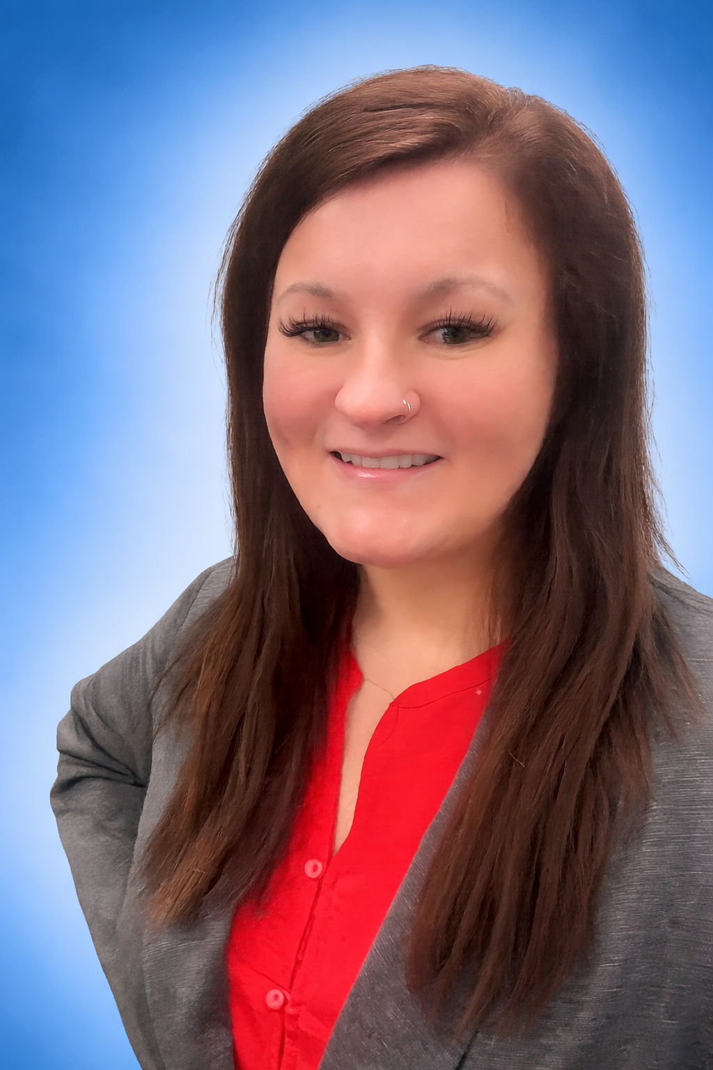 A woman wearing glasses and a hoodie is smiling for the camera.