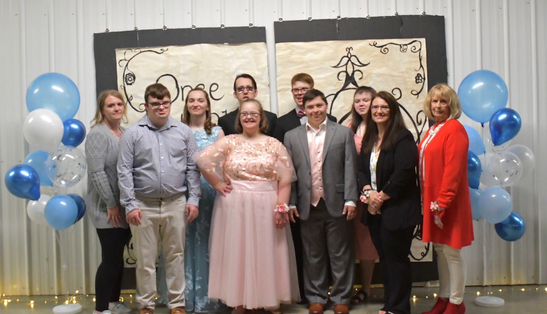 A group of people are posing for a picture in front of balloons.